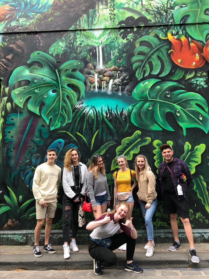 Group of people posing in front of a graffiti mural.