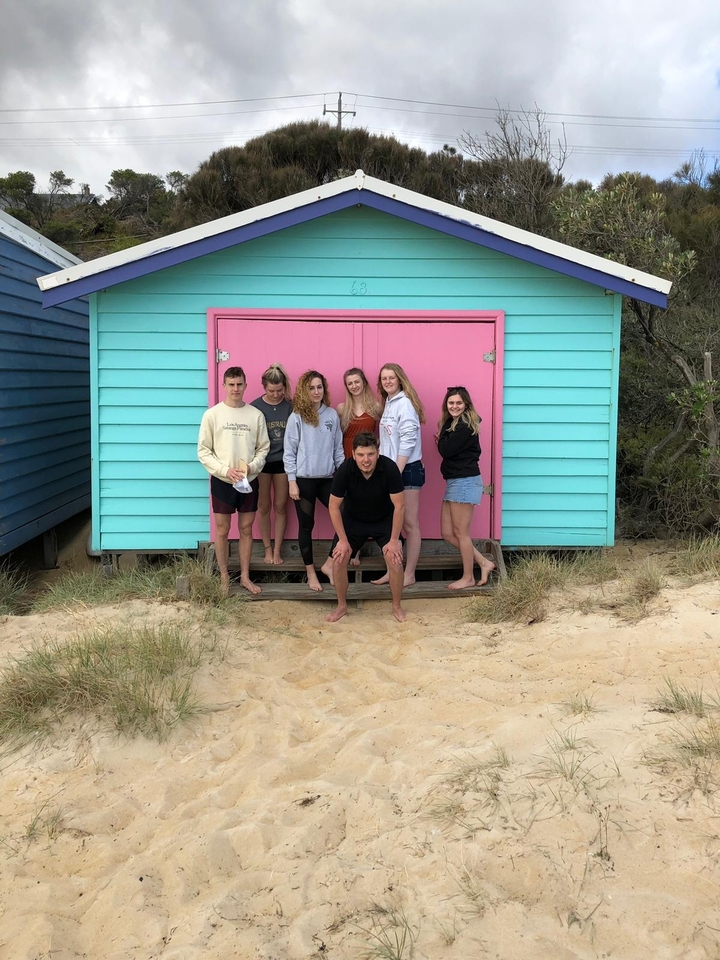 Group of people in front of brightly colored beach huts.