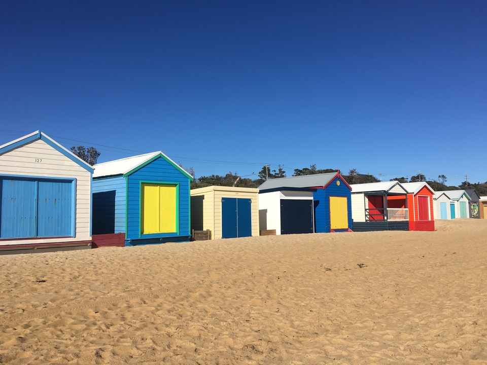 Colorful beach huts lined up on a sandy beach.