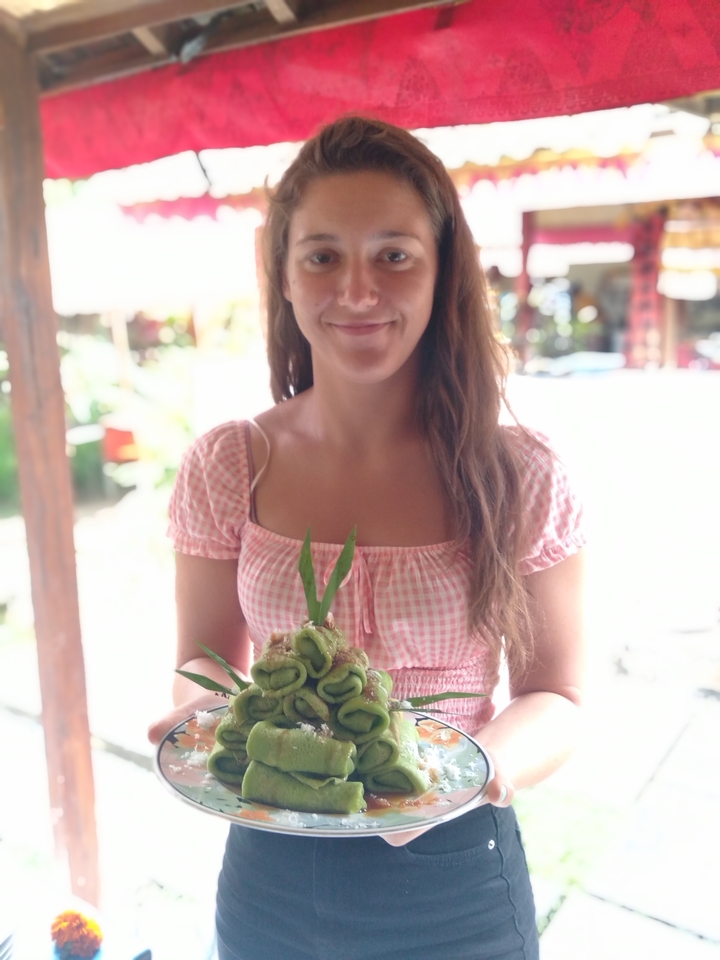 Femme tenant une assiette de fruits verts dans un cadre décontracté.
