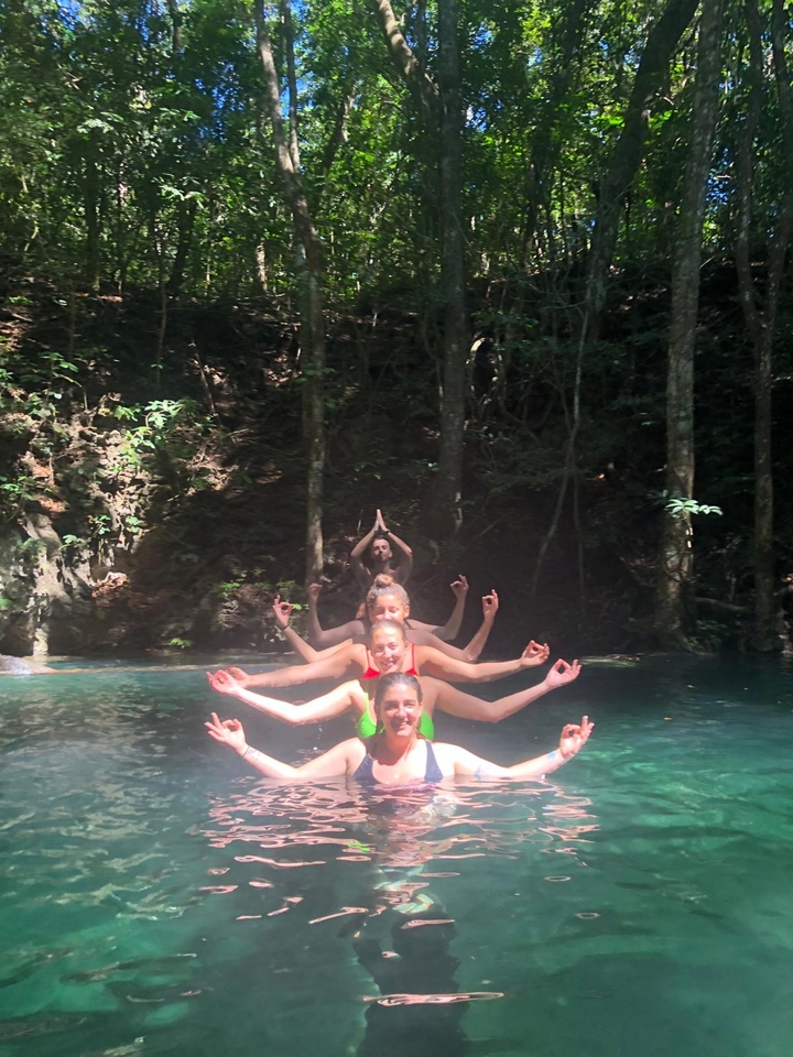 Des personnes dans un ruisseau en forêt pratiquant le yoga.
