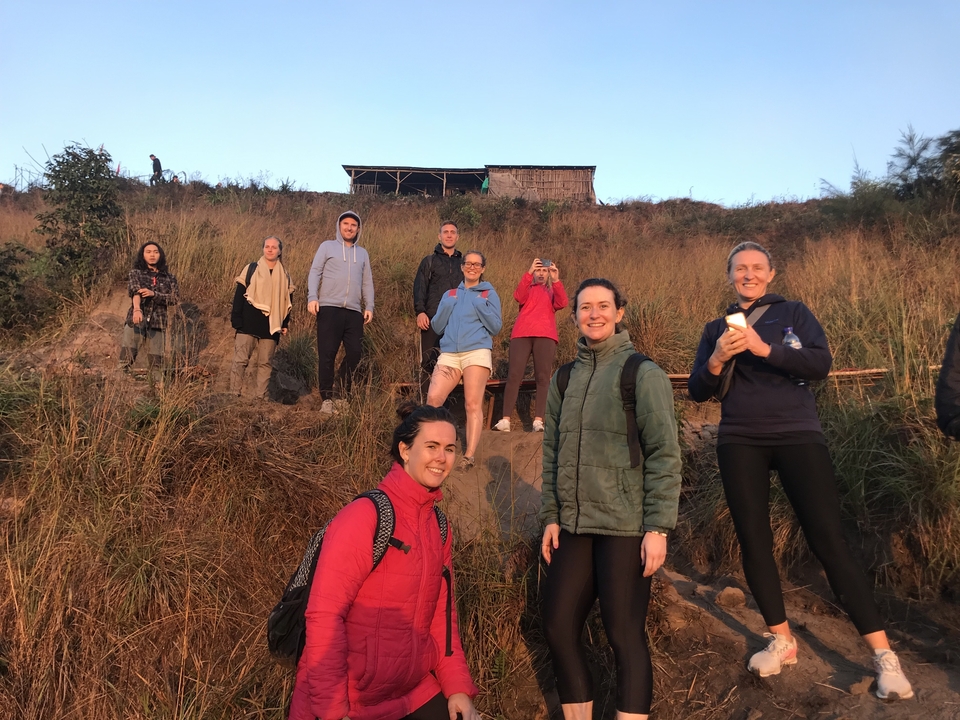 Group of people taking pictures on a hillside pathway.