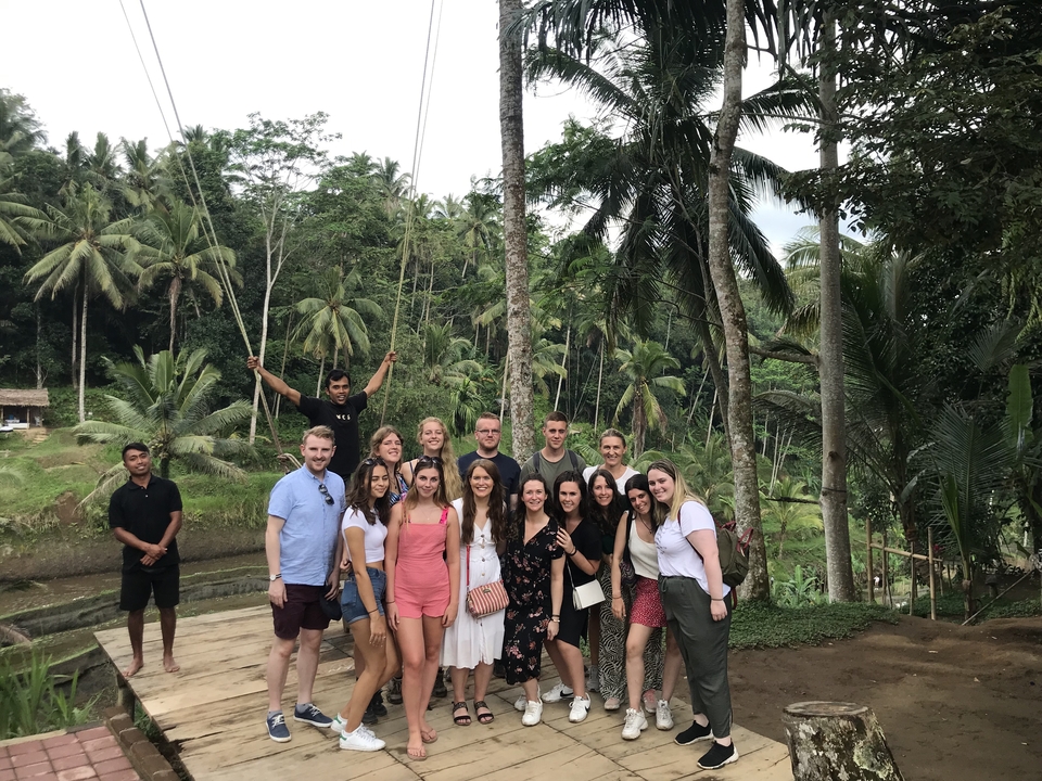 Tourists posing in a lush, tropical setting with a swing in the background.