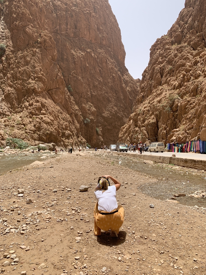 Rugged landscape of Todra Gorge with people and vehicles.