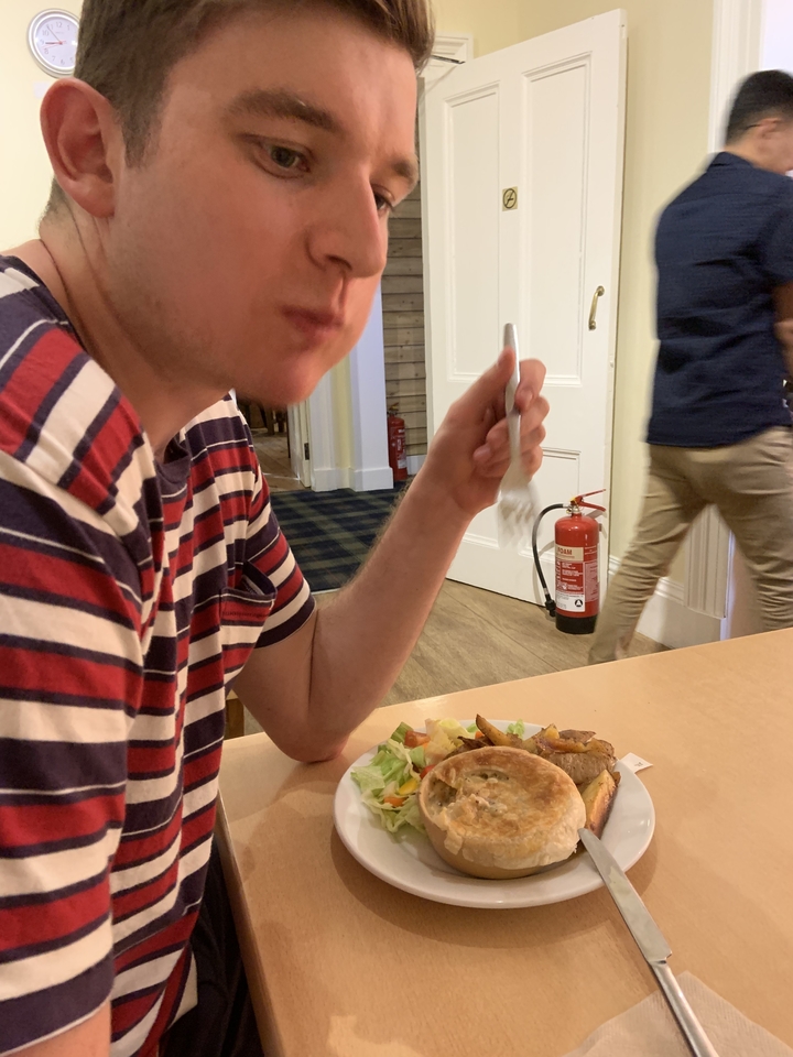 Une personne qui mange à une table à l'intérieur avec un extincteur visible.