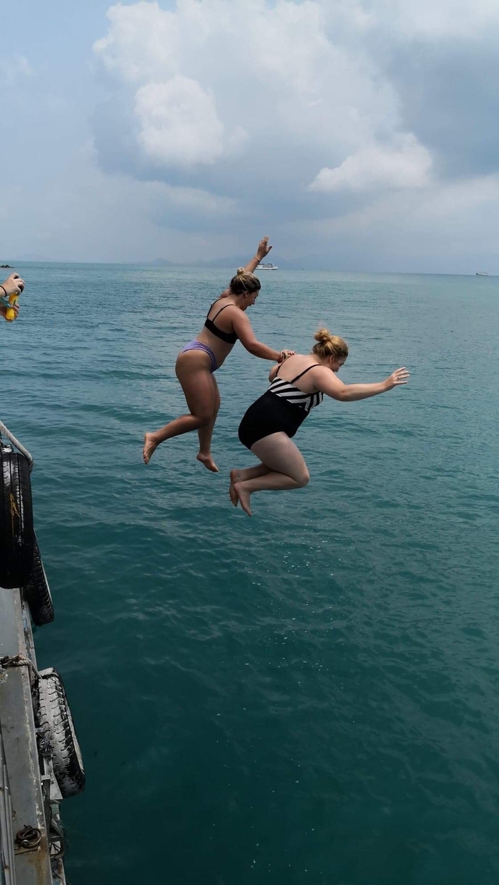 Two people jumping into the sea from a boat.