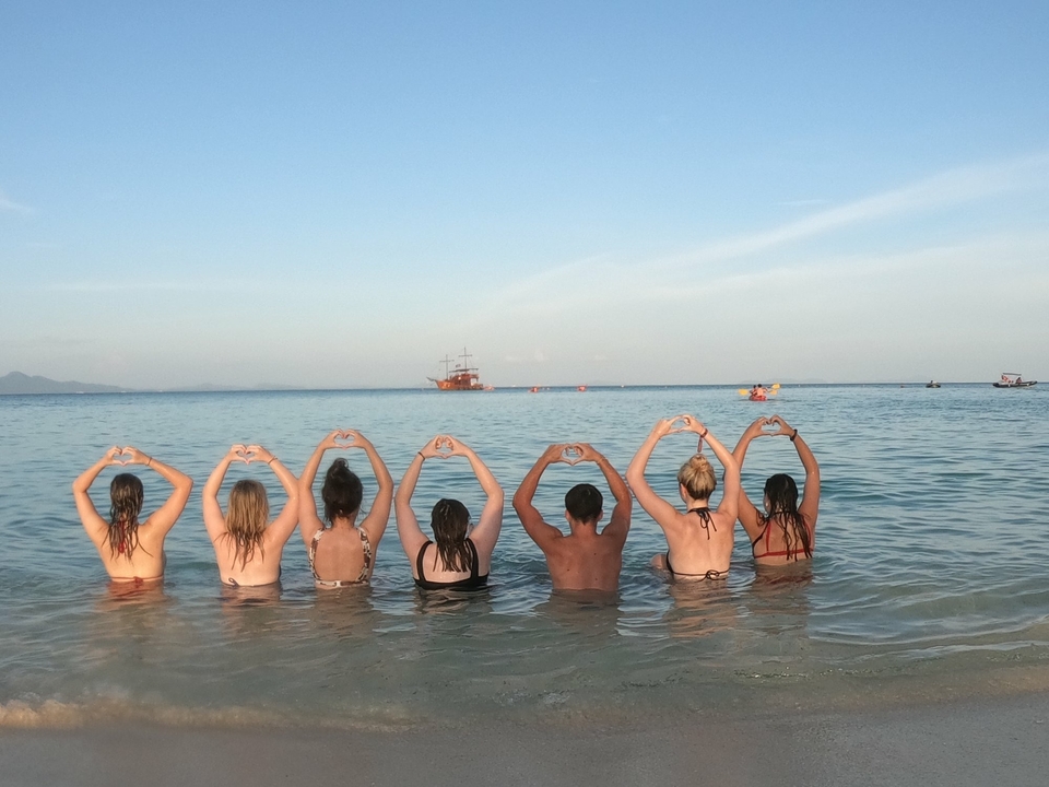 Group of people in water forming heart shapes with hands