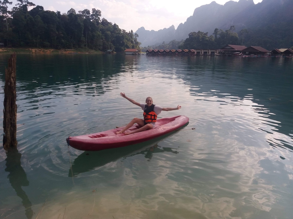 Person kayaking on a lake surrounded by lush greenery.