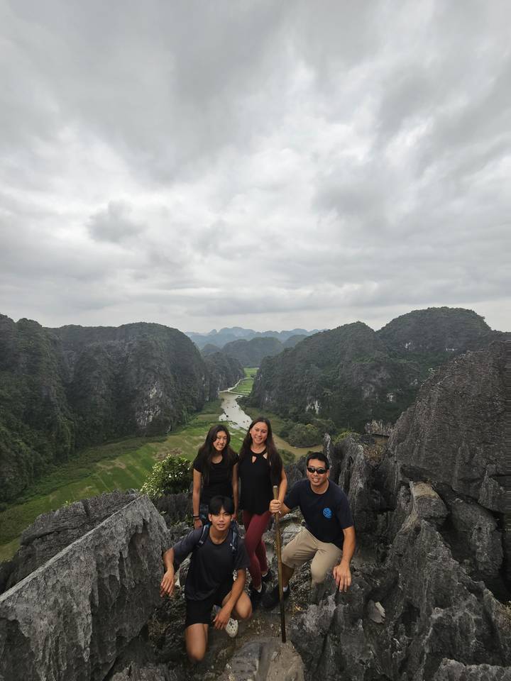 Groupe de personnes debout sur une colline rocheuse avec des vues verdoyantes.