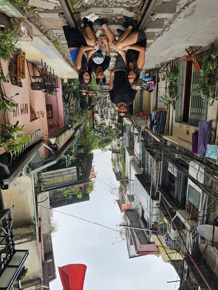 Groupe de personnes assises sur des rails de train dans une rue urbaine étroite.