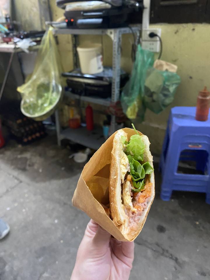 Translation from English to French:

"Gros plan d'un sandwich bánh mì tenu à la main."

Note: "Bánh mì" remains unchanged as it's the Vietnamese name for this specific type of sandwich, commonly used in French as well.