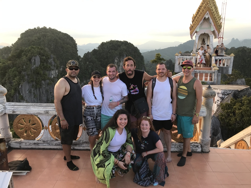 Group of people posing at a viewpoint with mountains.