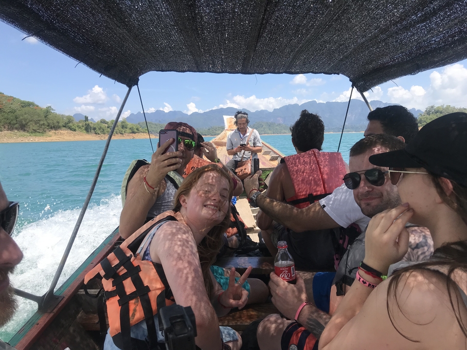 Group of people on a boat wearing life jackets with mountains in the background.