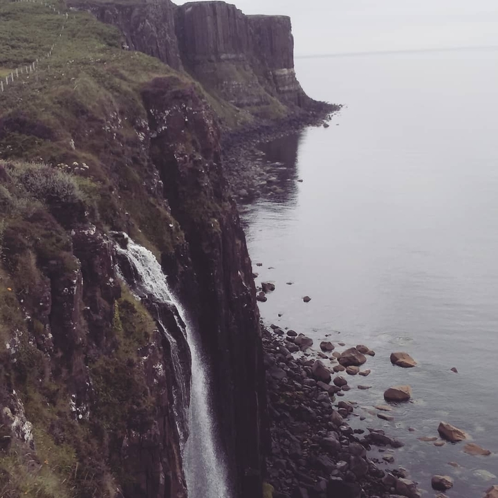 Cliffs with a waterfall leading into the ocean.