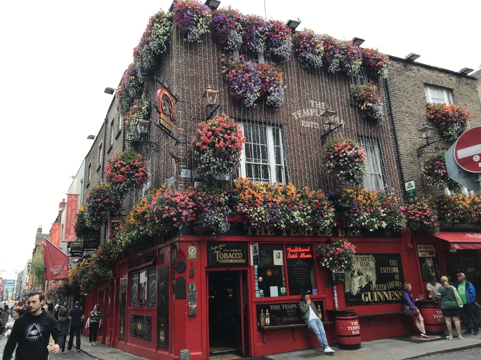 A lively pub exterior decorated with numerous colorful flowers.
