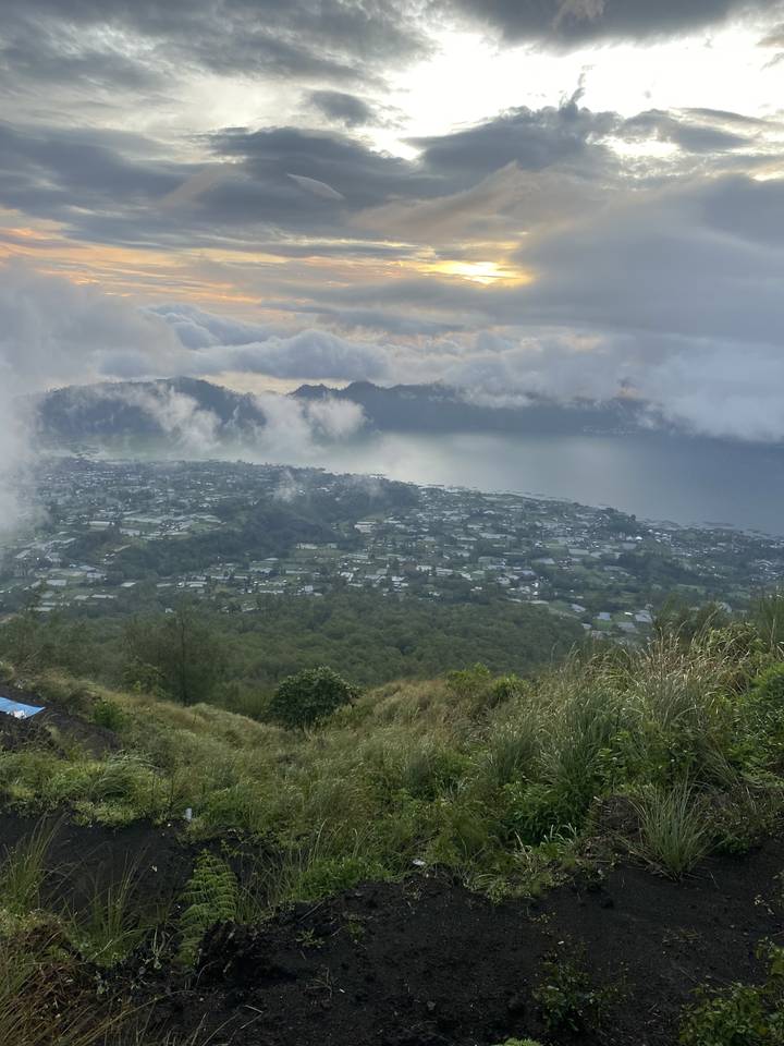 A view of a town from a hillside at sunset.