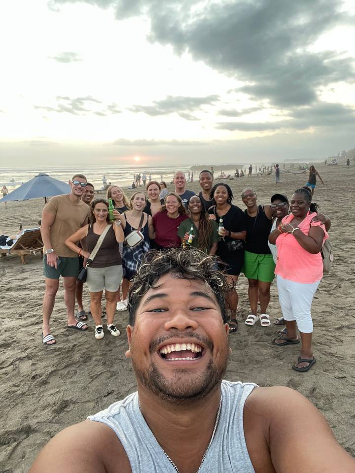 Group taking a selfie at the beach during sunset.