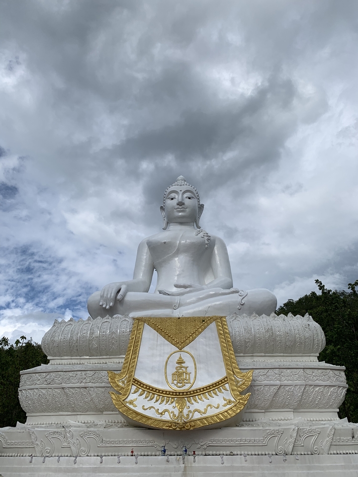 A large white Buddha statue under a cloudy sky.