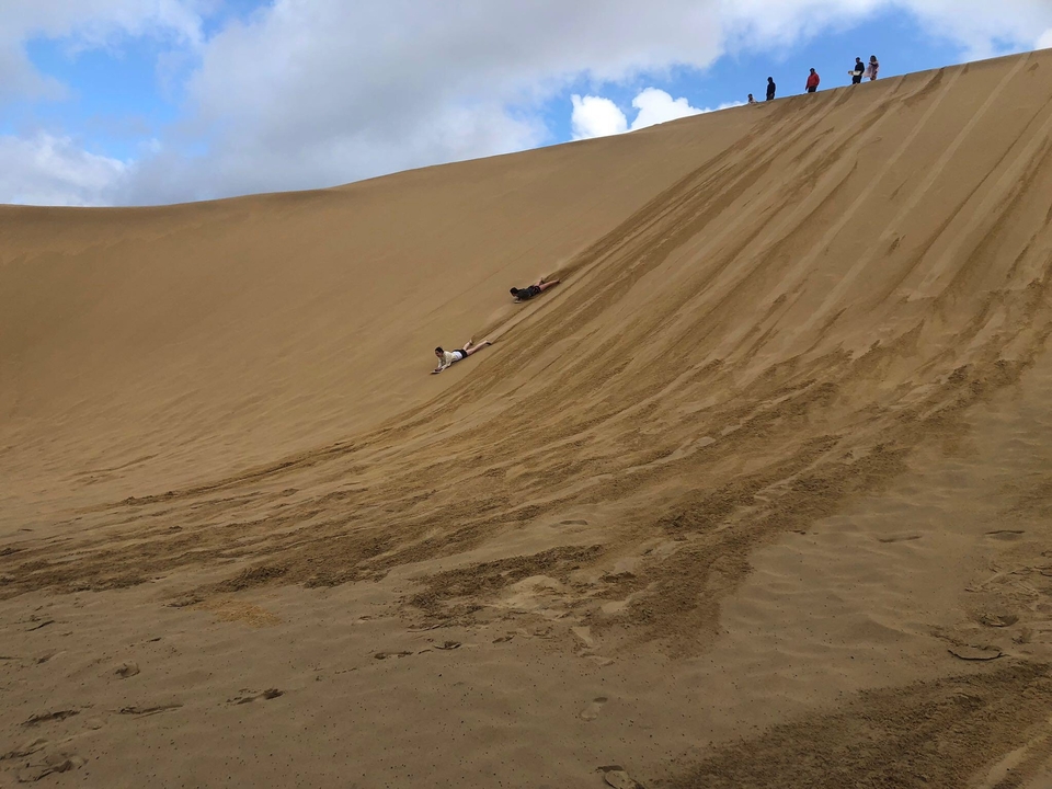 Personnes glissant le long d'une dune de sable.