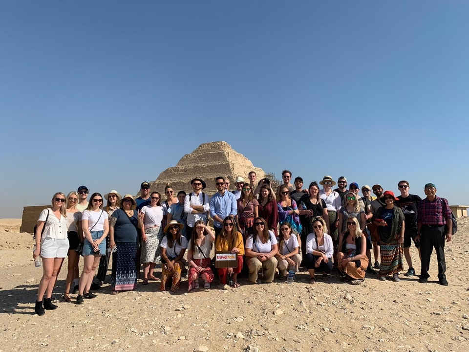 Large group photo with a desert pyramid in the background.