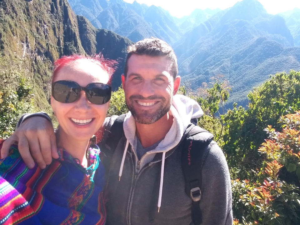 Deux personnes souriantes avec un paysage montagneux en arrière-plan.