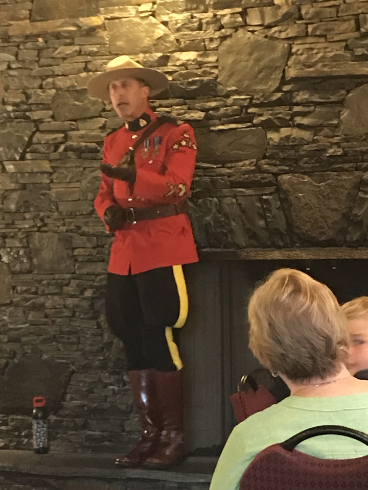 Mountie in traditional uniform speaking indoors.