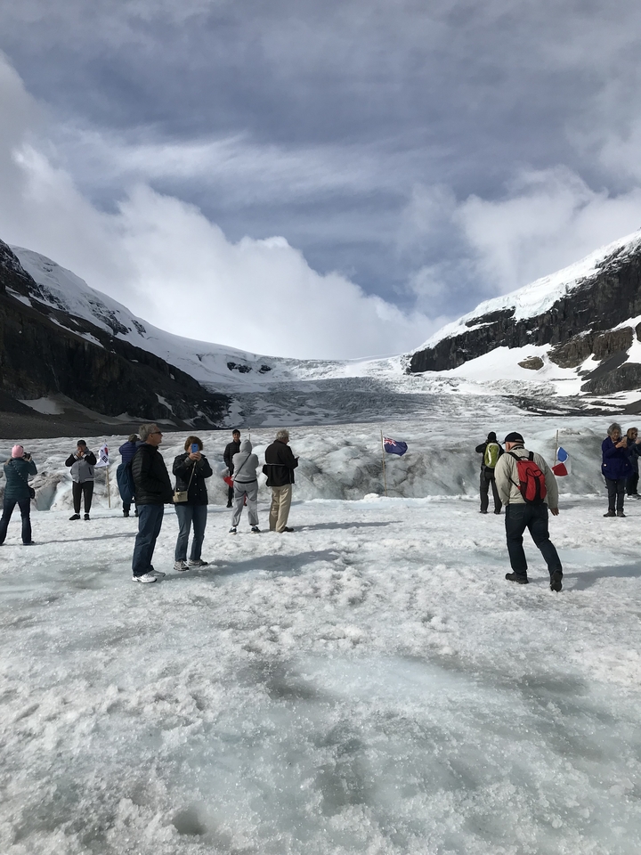 People standing and taking photos in a snowy mountainous area.