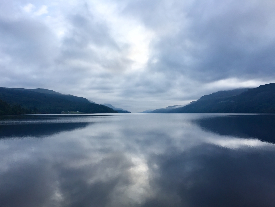 Calm lake with symmetrical reflection of cloudy sky.