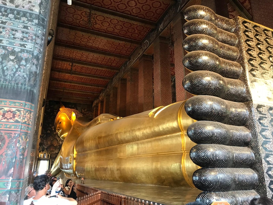 Reclining Buddha statue in a temple with intricate decor.