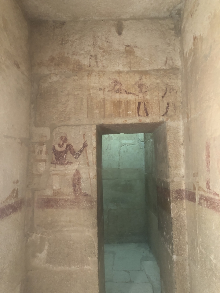 Interior of an ancient tomb with wall carvings and paintings.