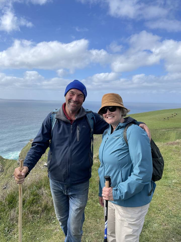 Two people posing with ocean cliffs in the background.