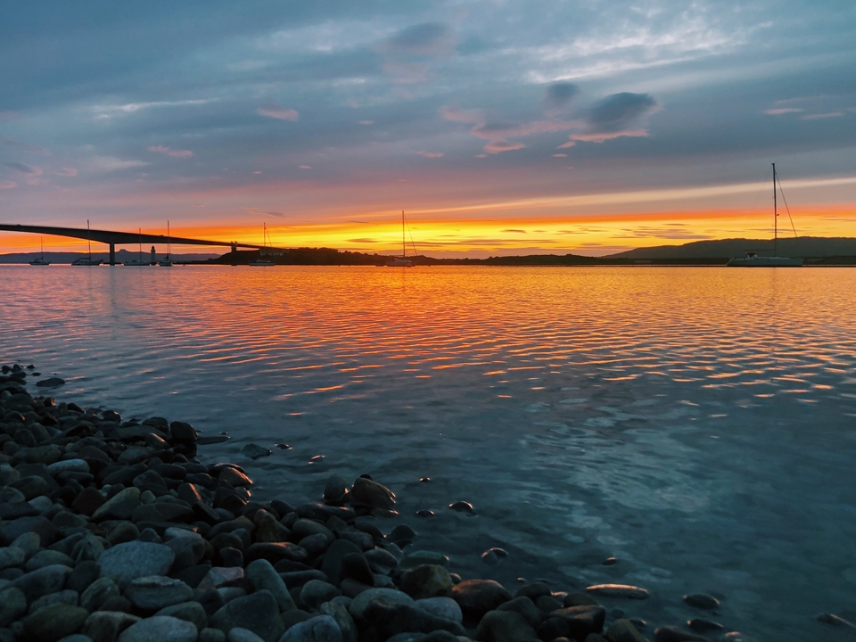 Vivid sunset over calm waters with reflected colors.