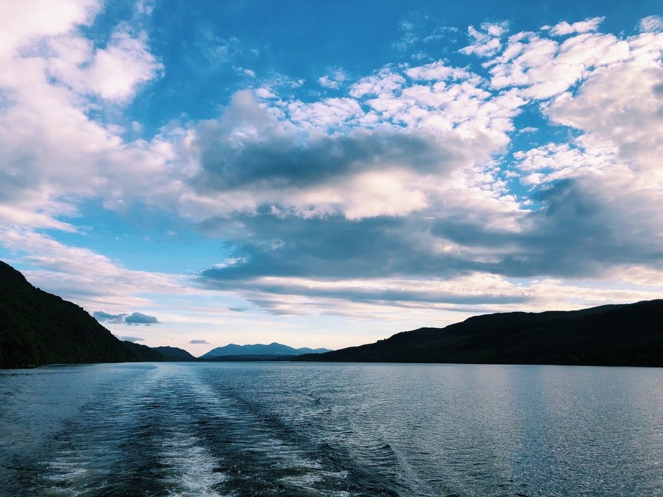 Mountainous lake scene with blue sky and clouds.