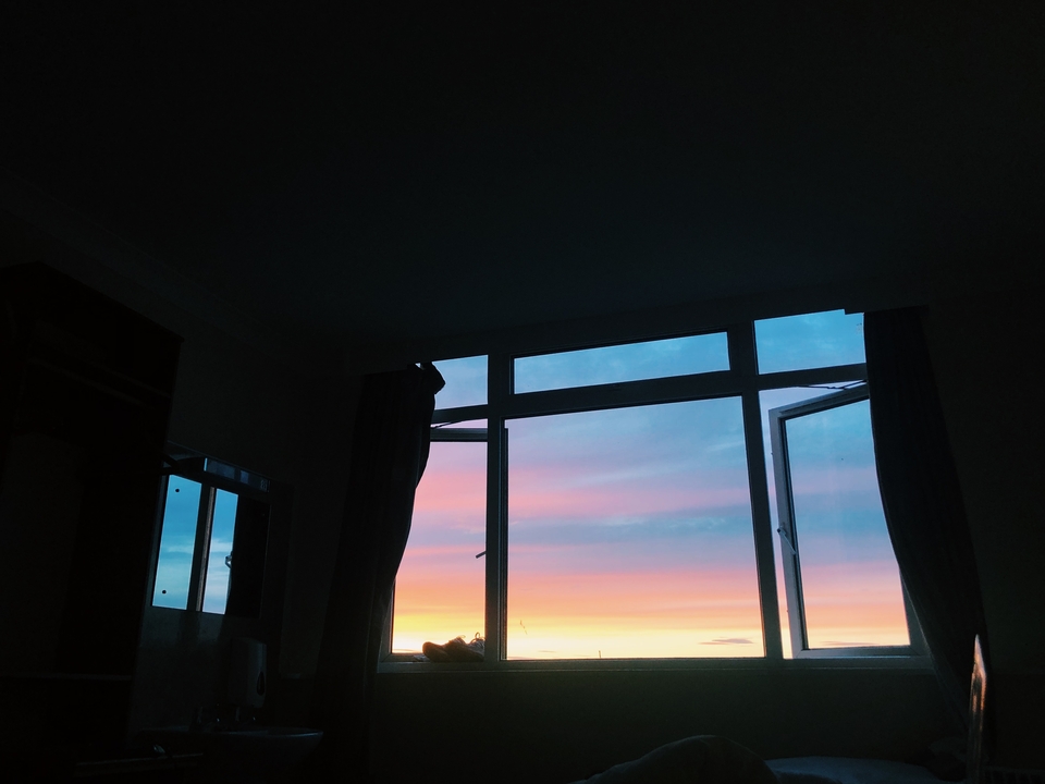 Vue du coucher de soleil à travers une fenêtre avec un ciel coloré.