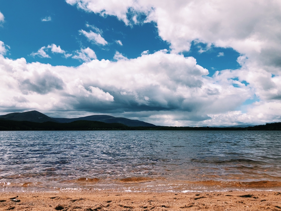 Lake scene with mountains under a cloudy sky.