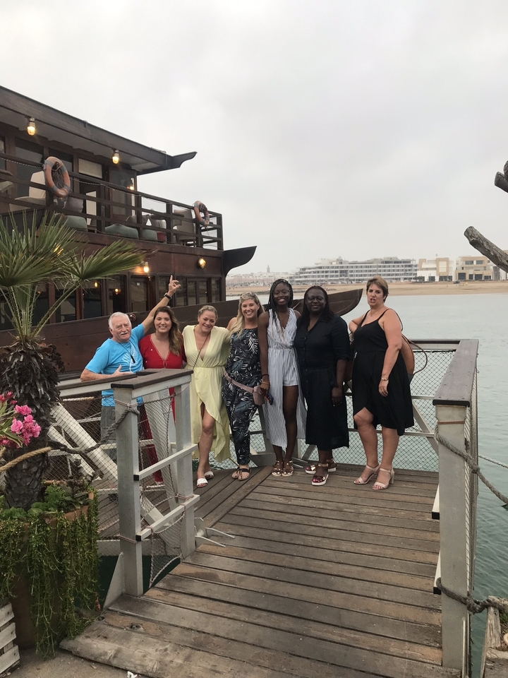 Group of people posing near a docked boat.