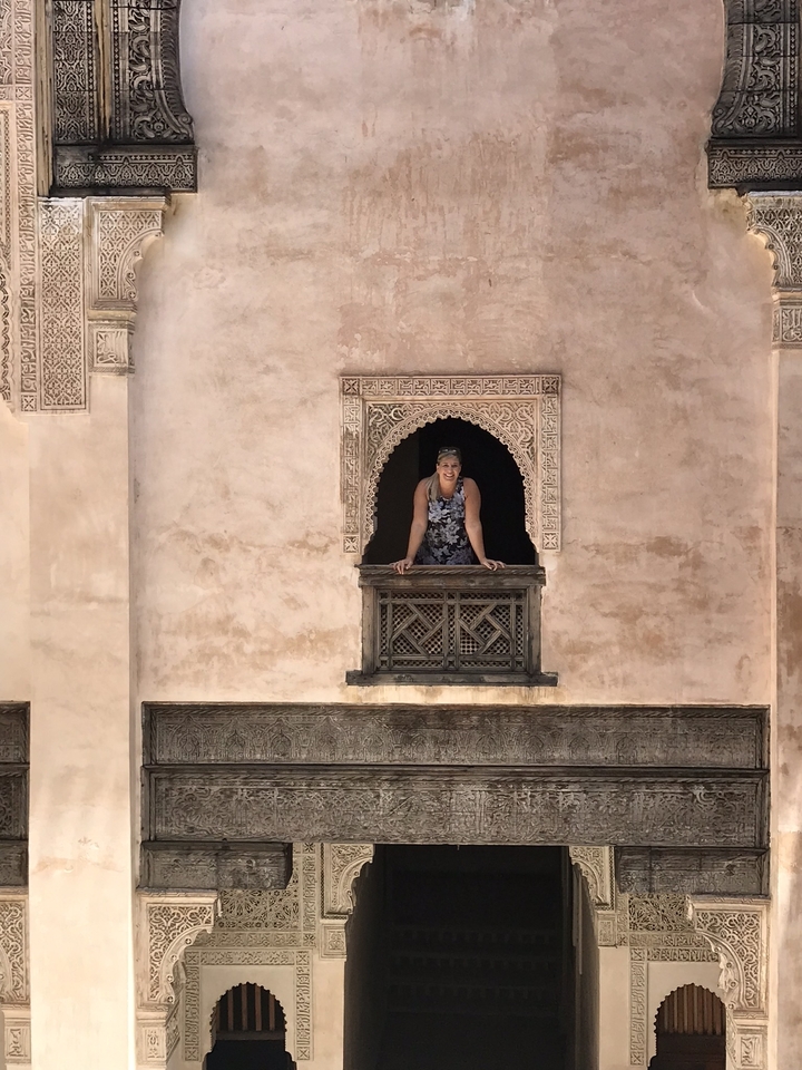 Woman looking out from a decorative balcony in a traditional building.