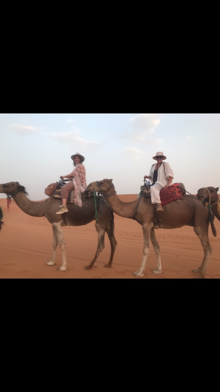 Two people riding camels in the desert.