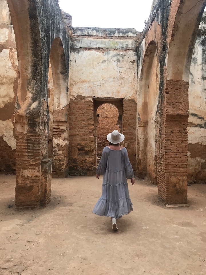 Woman in a hat exploring ancient stone ruins.