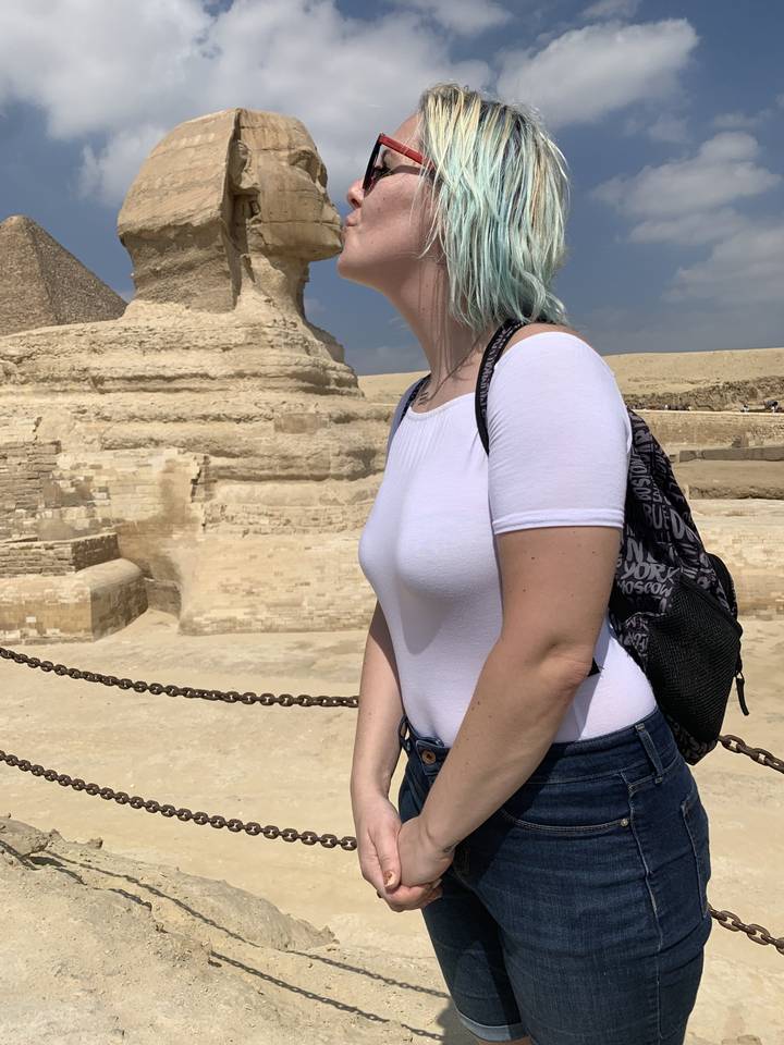 Person standing near a large stone statue in Egypt.