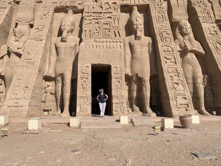 Person standing in front of statues carved into rock.