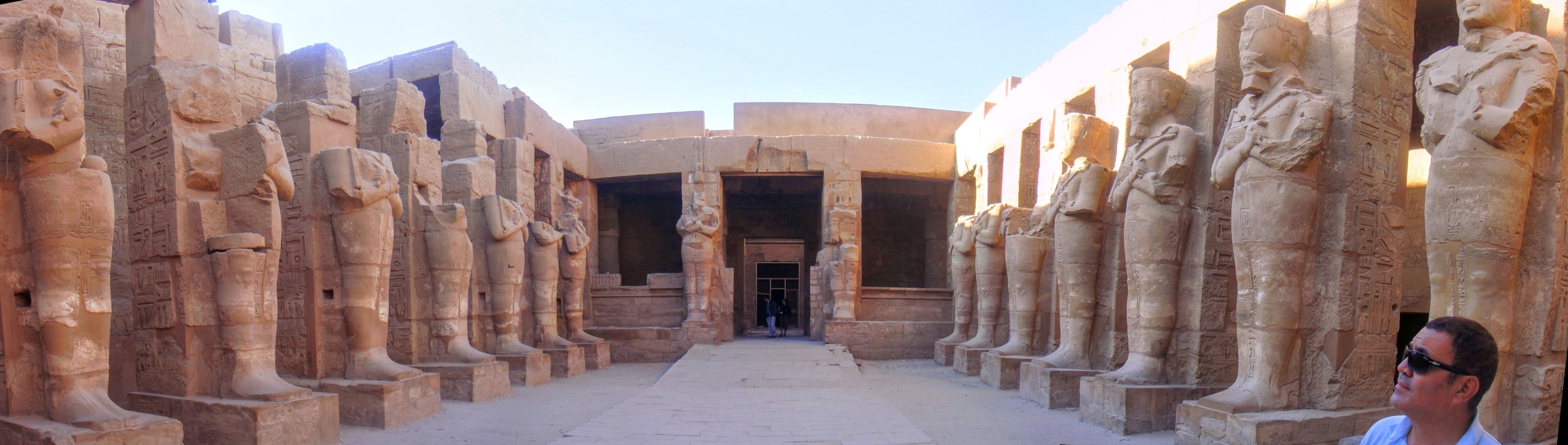 Ancient ruins with large stone statues lining the entrance.