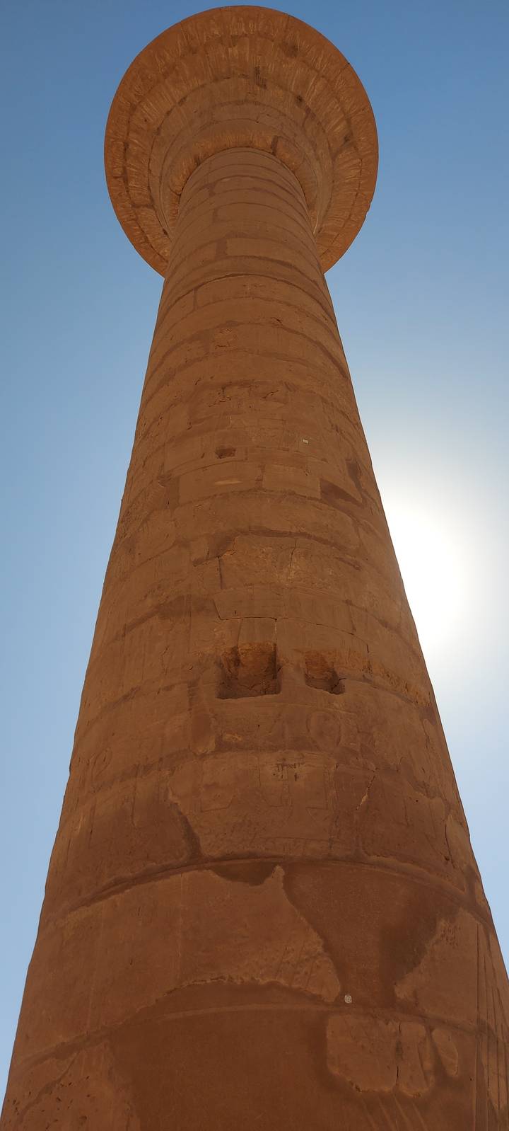 Tall ancient column with inscribed patterns viewed from below.