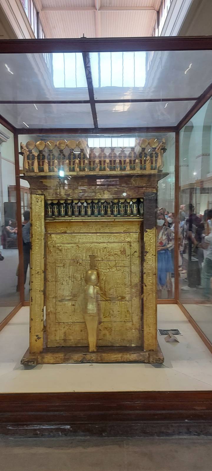 Golden artefact displayed in a glass case with reflections.