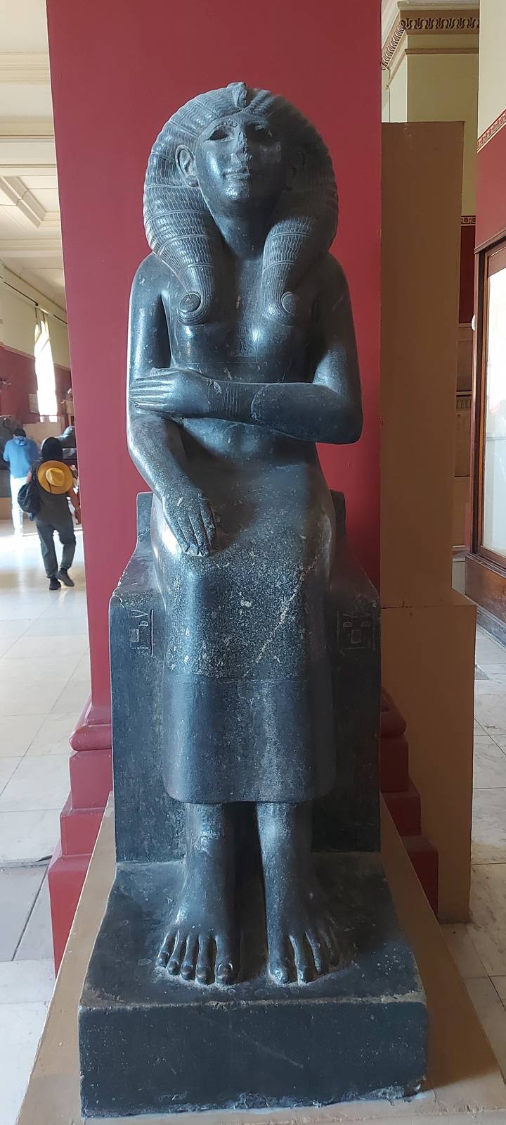 Dark stone statue of an ancient figure in a museum.