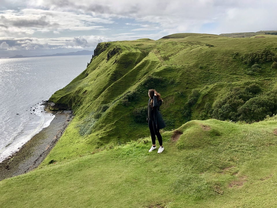 Person overlooking a scenic coastal landscape with cliffs.