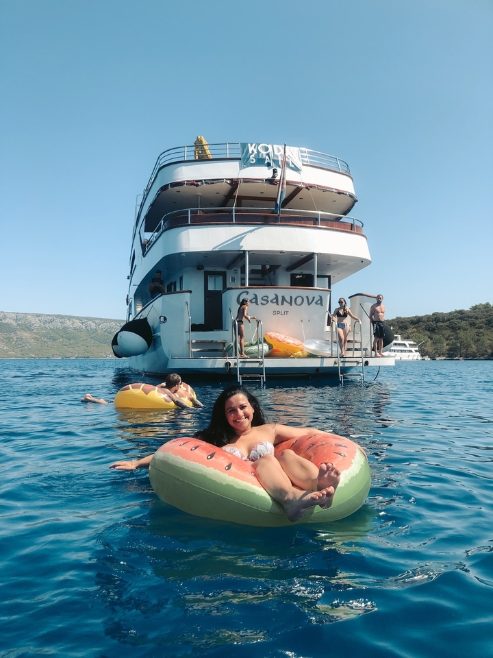 Des gens profitant d'activités aquatiques près d'un yacht avec des flotteurs gonflables.