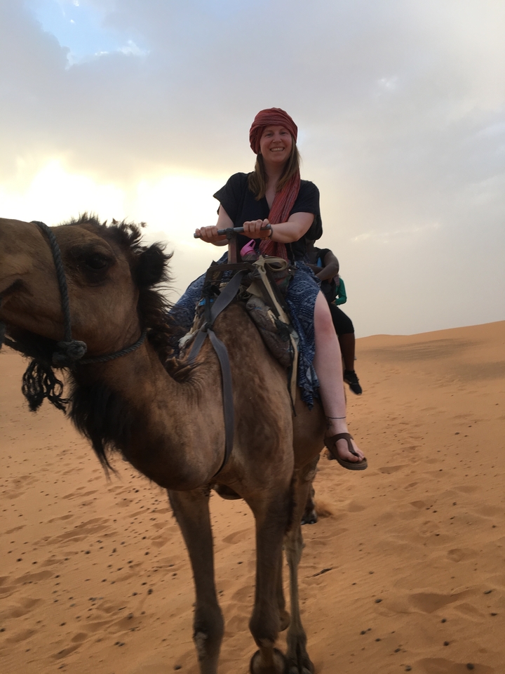People riding camels in a desert area.