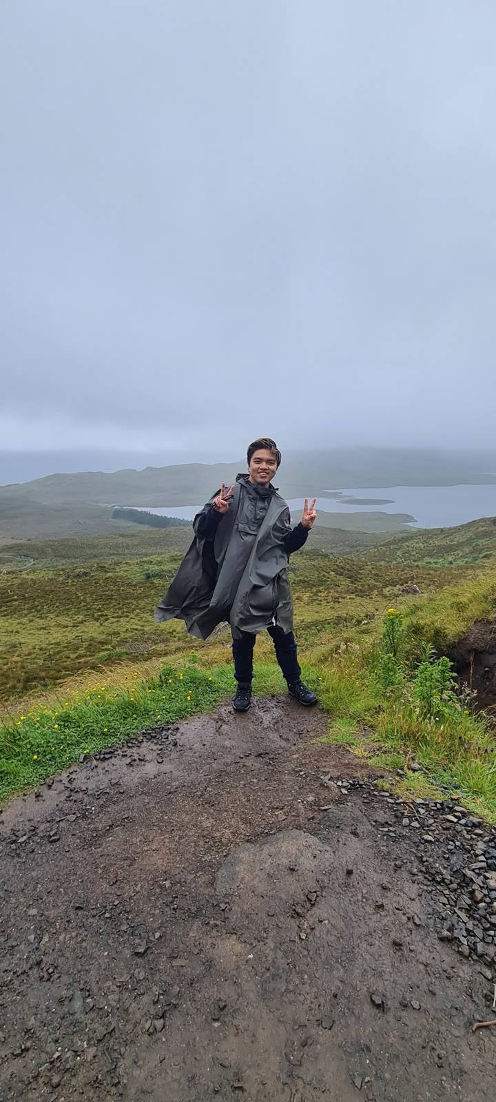 Man in hiking attire posing with a peace sign on a trail.