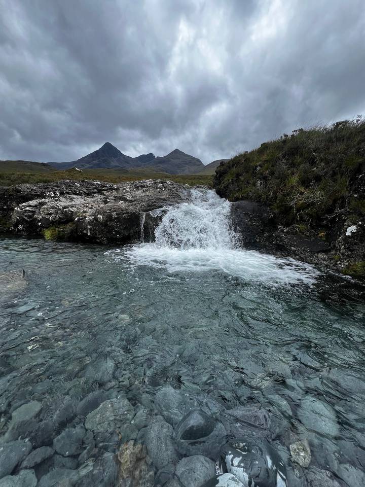 Clear stream with rocks and mountains.